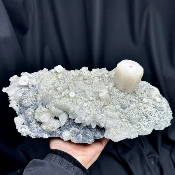 Large quartz druse plate with hexagonal calcite prism from Fujian, China, held in two hands
