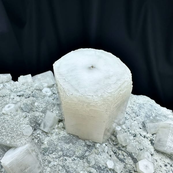 Large quartz druse plate with hexagonal calcite prism from Fujian, China, held in two hands, reverse side