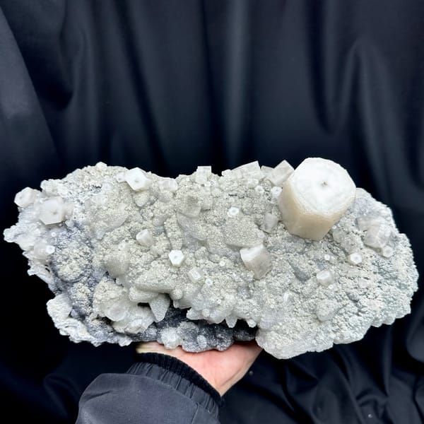 Large quartz druse plate with hexagonal calcite prism from Fujian, China, held in two hands, top view