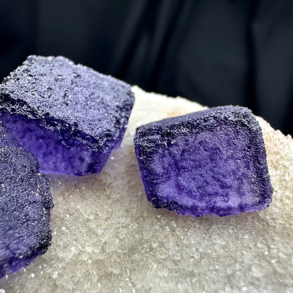 Four deep purple fluorite cubes on cream quartz matrix from Guizhou, China, reverse side