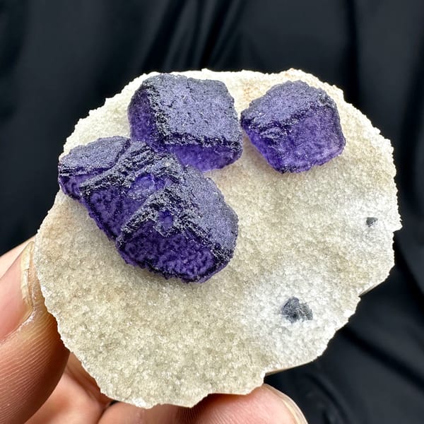 Four deep purple fluorite cubes on cream quartz matrix from Guizhou, China, top view