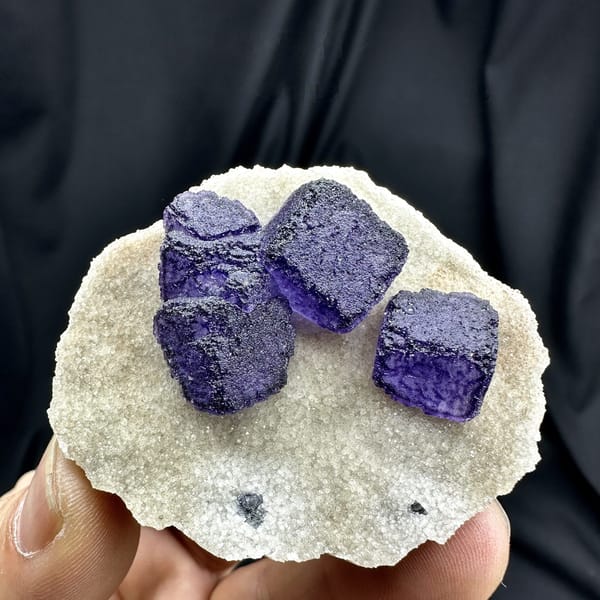 Four deep purple fluorite cubes on cream quartz matrix from Guizhou, China, detail of the matrix contact