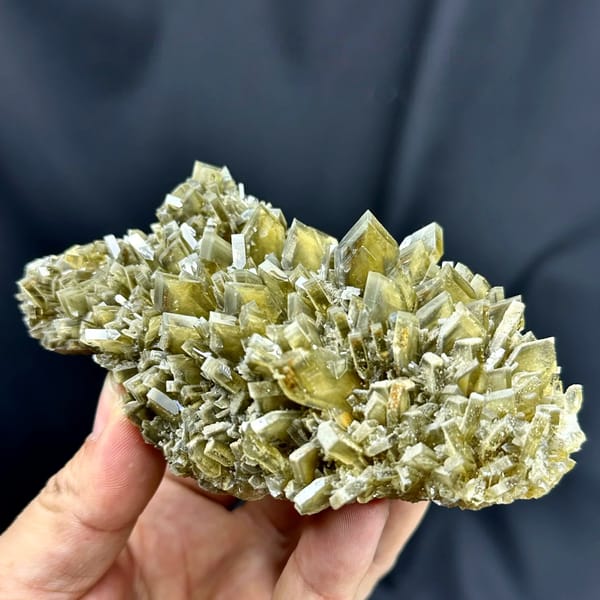 Cluster of straw-yellow bladed baryte crystals from Yunnan, China, held in hand