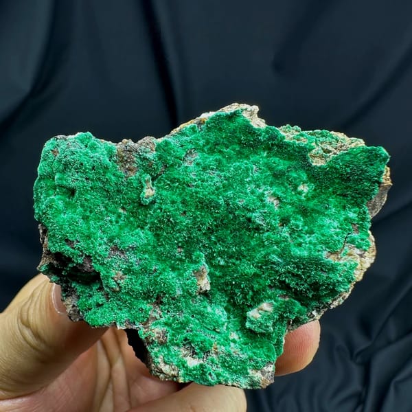 Velvet green moss malachite covering a rounded matrix from Yunnan, China, held in hand