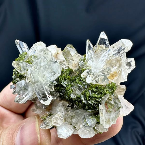 Transparent quartz cluster with green epidote from Sichuan, China, held in hand