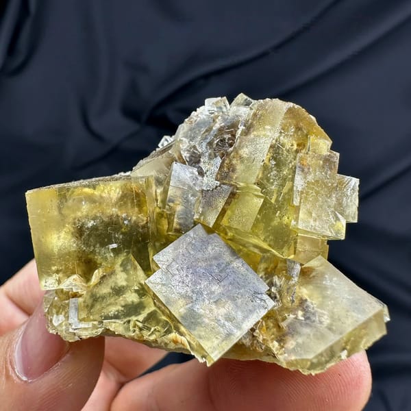 Honey-yellow fluorite cubes with blue cores and baryte from Beijing, China, held in hand