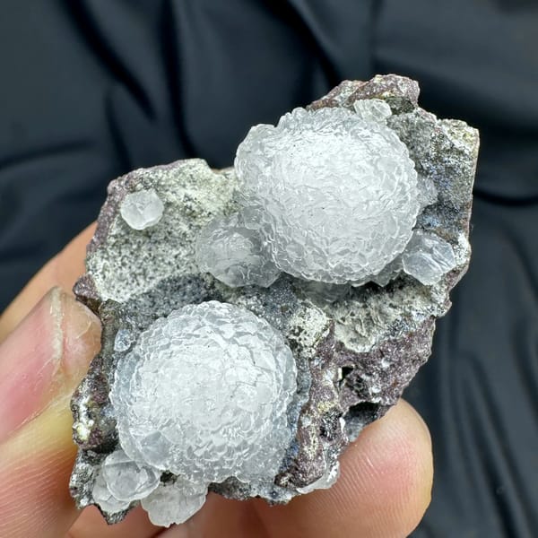 Two white botryoidal calcite spheres on grey matrix from Zhejiang, China, second angle