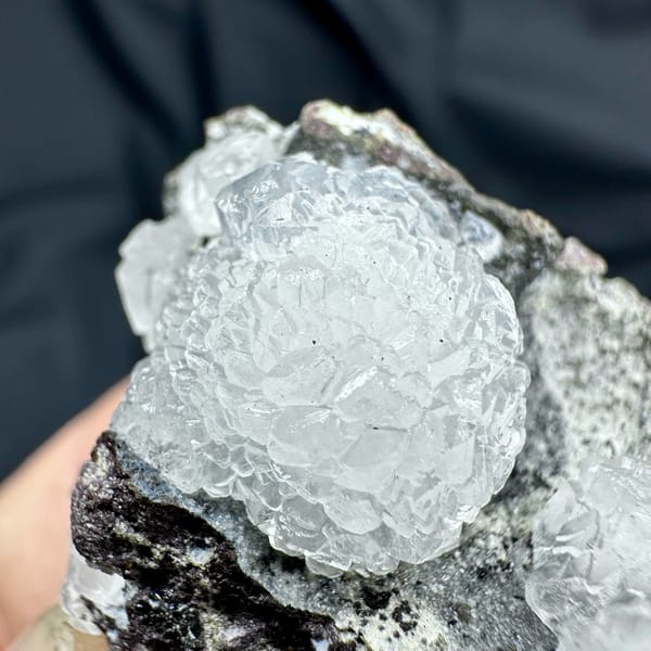 Two white botryoidal calcite spheres on grey matrix from Zhejiang, China, reverse side