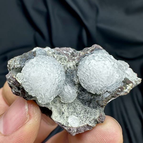 Two white botryoidal calcite spheres on grey matrix from Zhejiang, China, top view