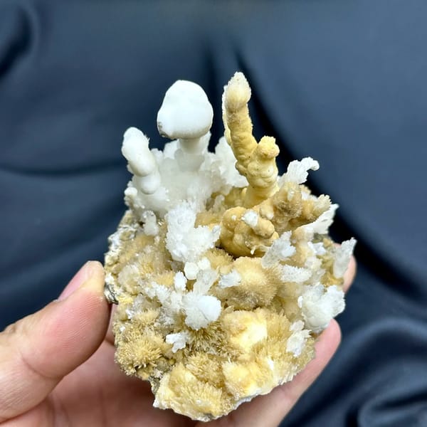 White aragonite spires on golden aragonite base from Guizhou, China, held in hand