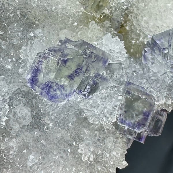 Glassy blue-green fluorite cubes on white quartz druse from Fujian, China, close-up of the crystal faces