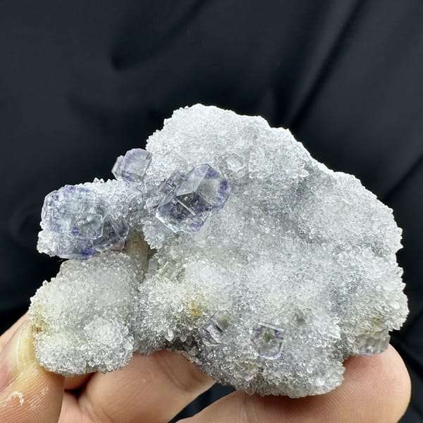 Glassy blue-green fluorite cubes on white quartz druse from Fujian, China, detail of the matrix contact