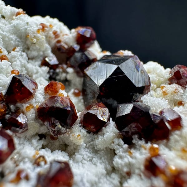 Wine-red garnet crystals with hyalite opal on feldspar from Yunxiao, Fujian, China, close-up of the crystal faces
