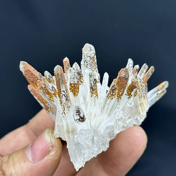 Fan of clear quartz prisms with orange-stained tips from Guangdong, China, held in hand