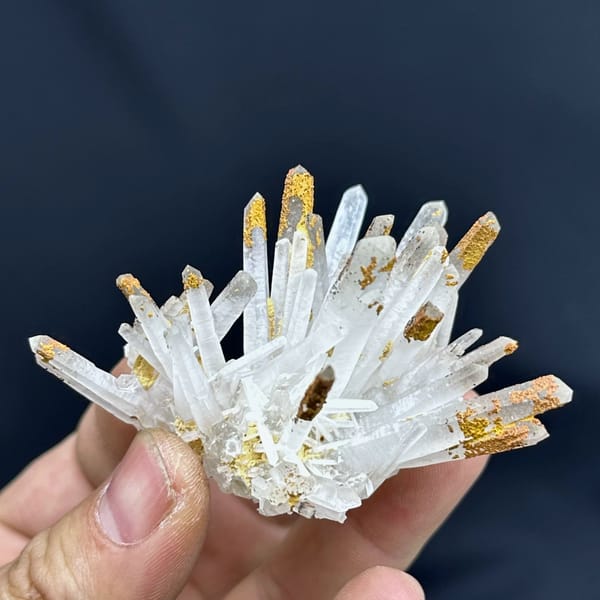 Fan of clear quartz prisms with orange-stained tips from Guangdong, China, close-up of the crystal faces