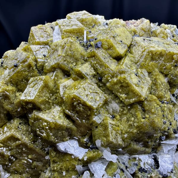 Olive-green grossular garnet crystals with white calcite blades from Inner Mongolia, China, close-up of the crystal faces