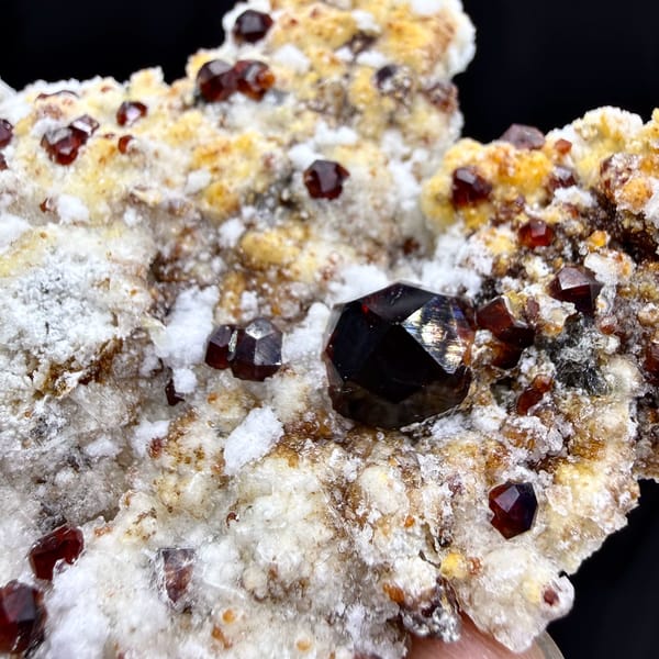 Large dark-red garnet crystals with hyalite opal on feldspar from Yunxiao, Fujian, China, close-up of the crystal faces