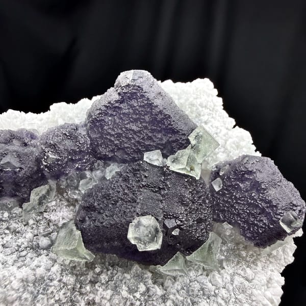 Muted purple recrystallised fluorite balls on white druse from Fujian, China, second angle