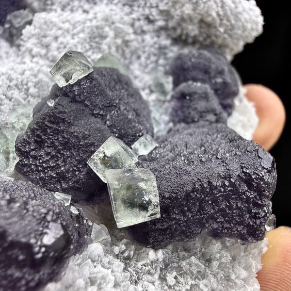 Muted purple recrystallised fluorite balls on white druse from Fujian, China, close-up of the crystal faces