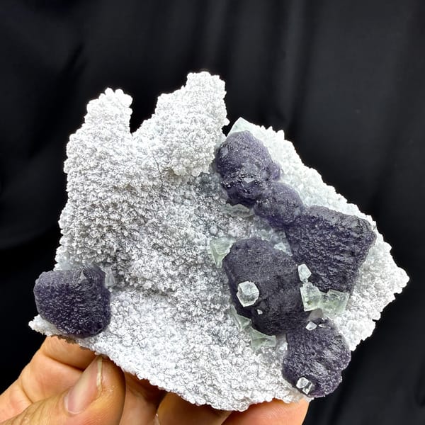 Muted purple recrystallised fluorite balls on white druse from Fujian, China, detail of the matrix contact