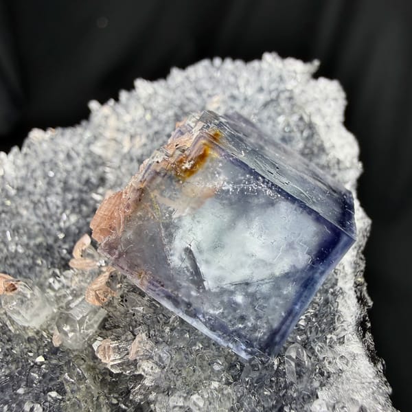 Blue-rimmed fluorite cube on grey quartz with pink rhodochrosite from Wuzhou, Guangxi, China, close-up of the crystal faces
