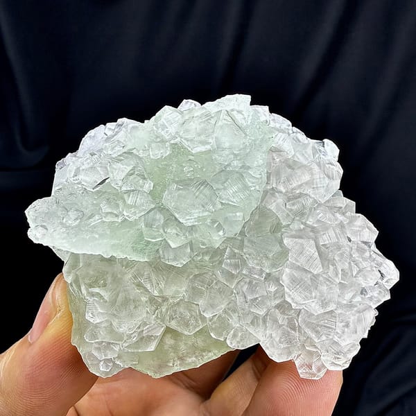 Green fluorite floater overgrown with clear calcite from Fujian, China, held in hand