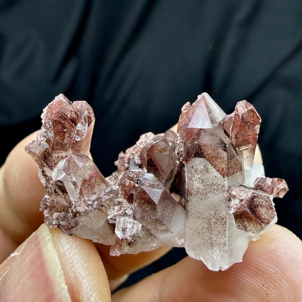 Clear quartz cluster with red hematite phantoms from Shanxi, China, held in hand