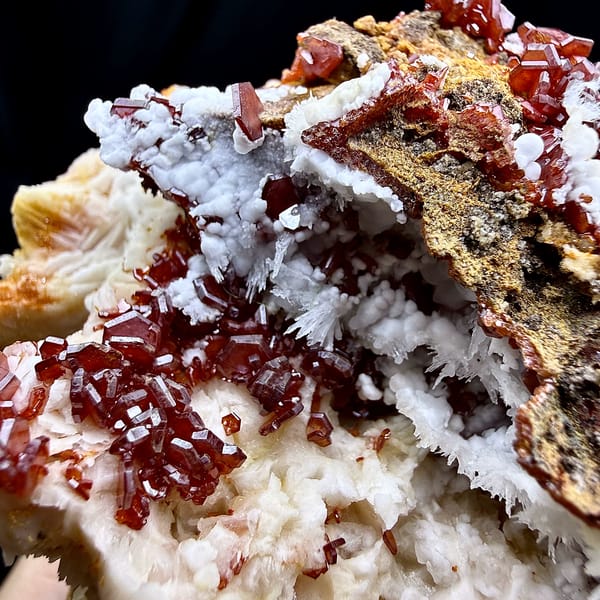 Red vanadinite crystals on brown baryte with white aragonite from Morocco, second angle
