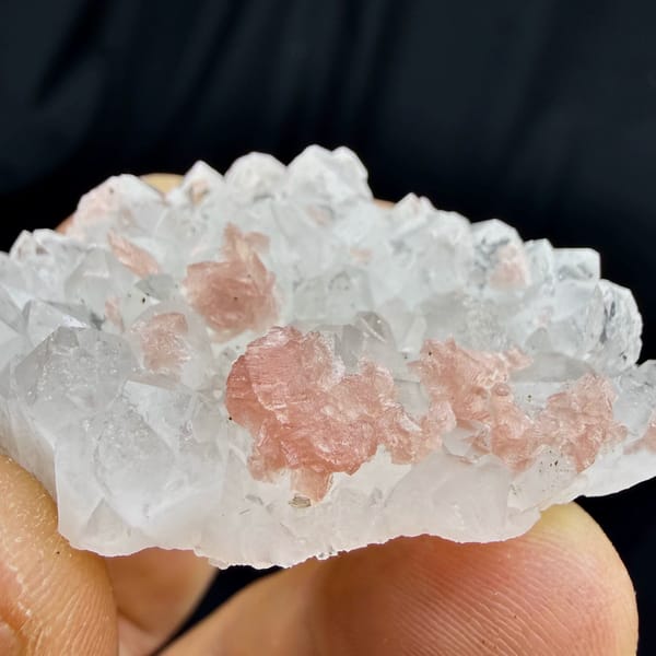 Pink rhodochrosite under frosted quartz crystals from Wuzhou, Guangxi, China, close-up of the crystal faces