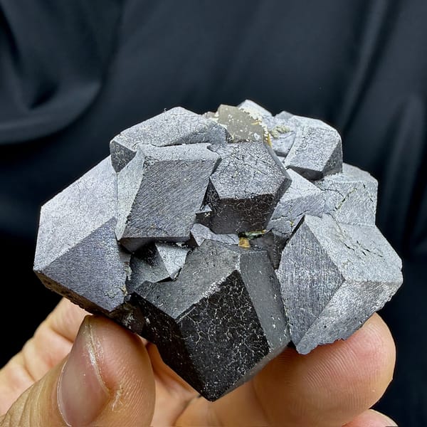 Cluster of large steel-grey magnetite crystals from Inner Mongolia, China, detail of the matrix contact