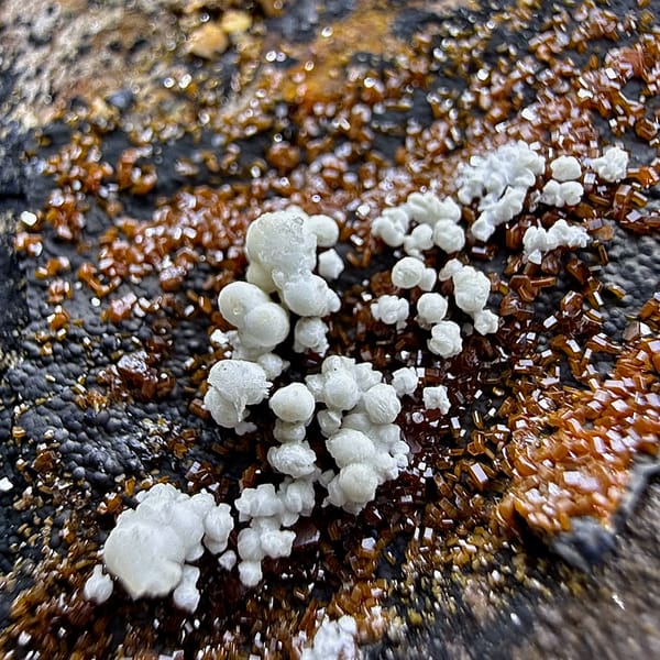 Slab covered in fine red vanadinite druse with aragonite from Morocco, close-up of the crystal faces