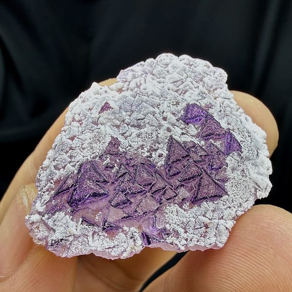 Deep purple triangular fluorite crystals in white aragonite from Yunnan, China, close-up of the crystal faces