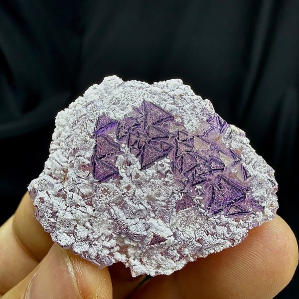 Deep purple triangular fluorite crystals in white aragonite from Yunnan, China, detail of the matrix contact