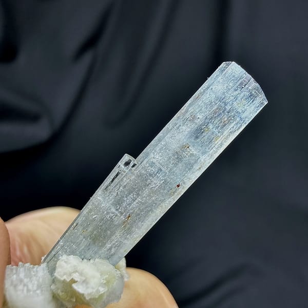 Sky-blue aquamarine prism standing on white feldspar from Namibia, close-up of the crystal faces