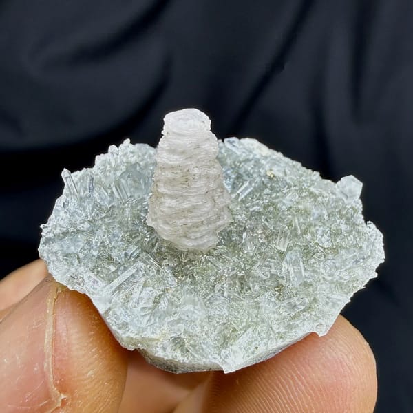 Stacked coin-shaped calcite tower on clear quartz needles from Fujian, China, held in hand