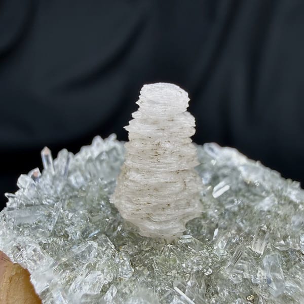 Stacked coin-shaped calcite tower on clear quartz needles from Fujian, China, close-up of the crystal faces
