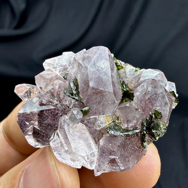 Strawberry-pink garden quartz crystals with green epidote from Sichuan, China, held in hand