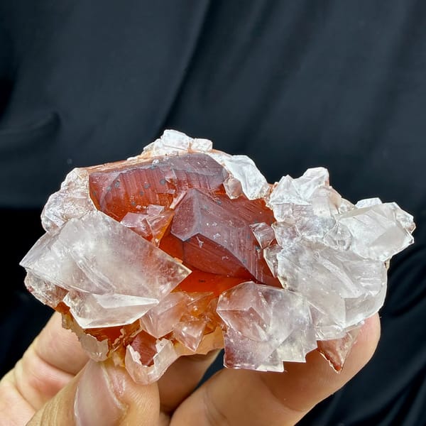 Red-skinned calcite core inside clear calcite crystals from Fujian, China, held in hand