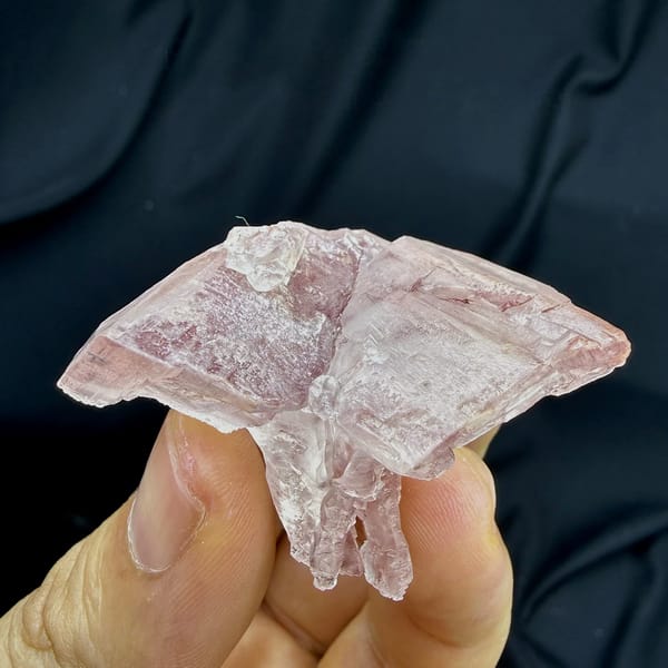 Pink lingzhi-mushroom shaped calcite floater from Guangdong, China, held in hand
