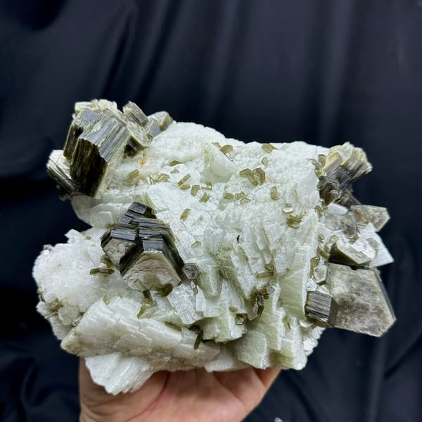 Large white feldspar block with bronze mica books from Pakistan, held in hand