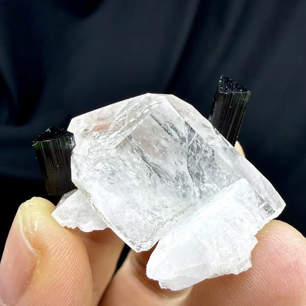Clear quartz crystal with green-tipped black tourmaline and feldspar from Pakistan, held in hand