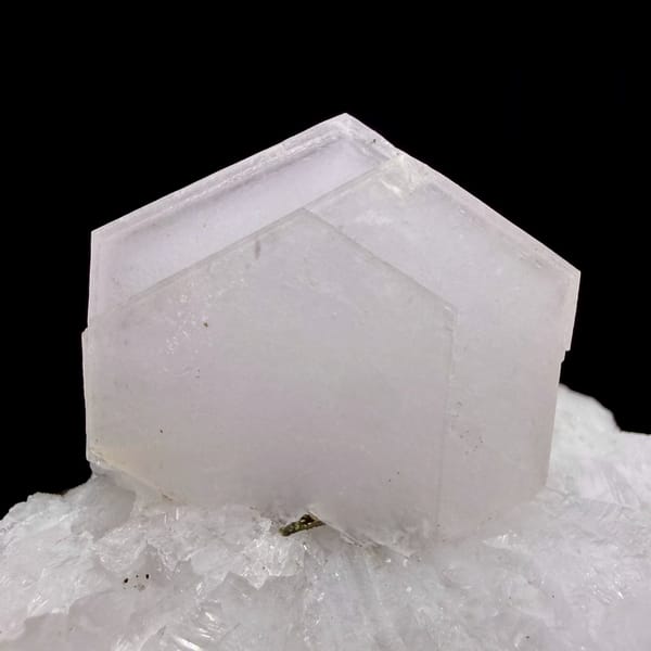 Pale pink hexagonal calcite crystal on white quartz from Fujian, China, close-up of the crystal faces