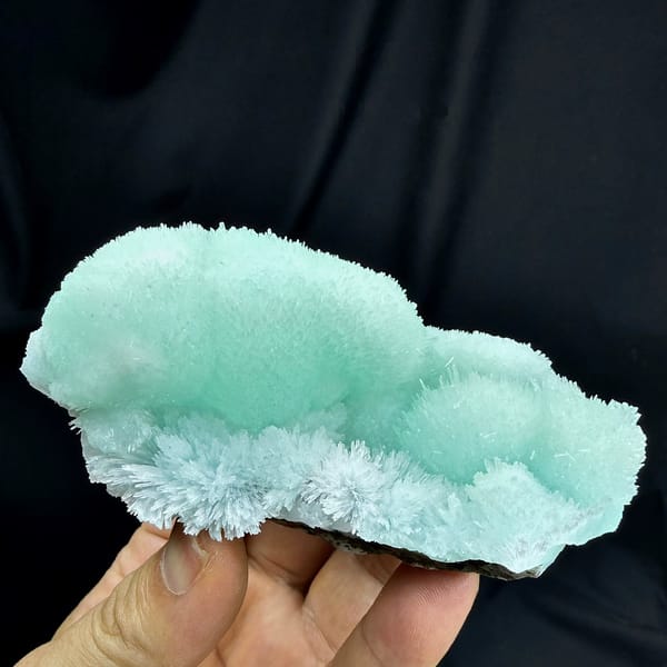 Aqua-blue acicular aragonite flower mounds from Yunnan, China, held in hand