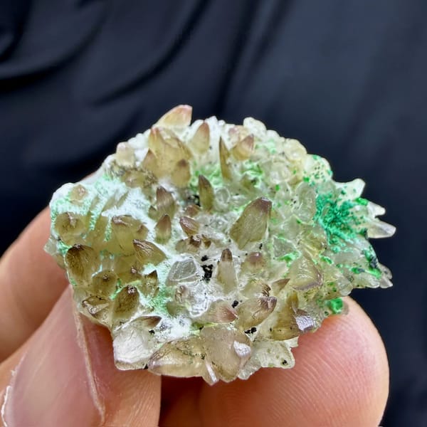 Dogtooth calcite with green copper minerals from Yunnan, China, held in hand