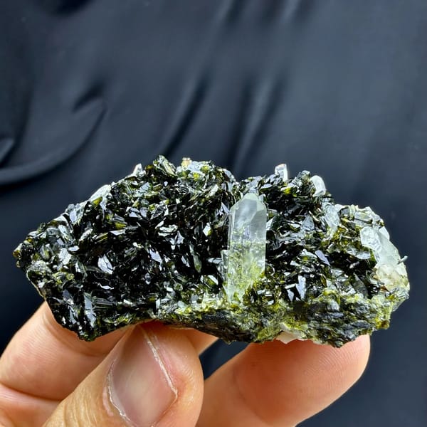 Clear quartz point standing in dark green epidote from Sichuan, China, held in hand