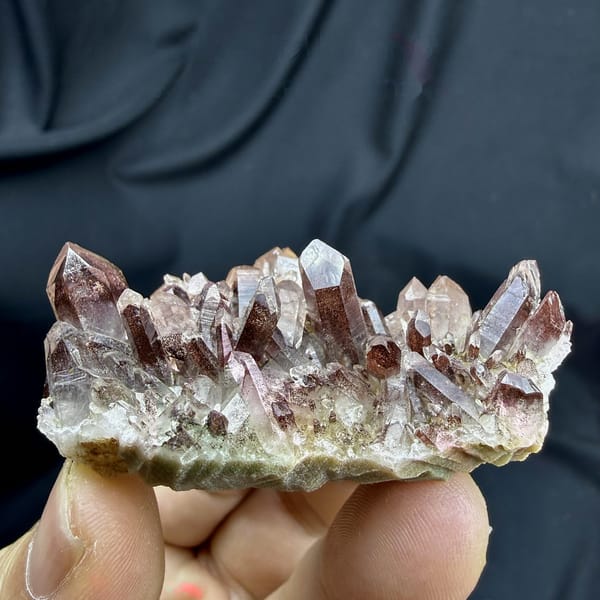 Row of clear quartz points with red hematite phantoms from Shanxi, China, detail of the matrix contact