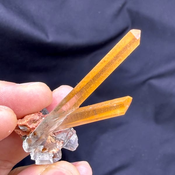 Two orange hematoid quartz needles on specular hematite from Guangdong, China, close-up of the crystal faces
