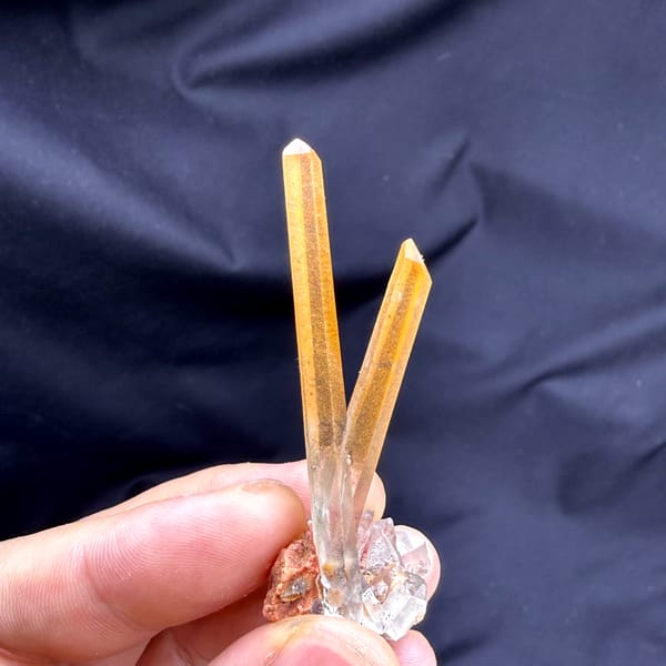 Two orange hematoid quartz needles on specular hematite from Guangdong, China, top view