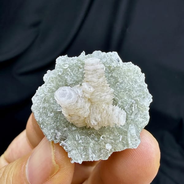 Stacked pagoda calcite tower on quartz needles from Fujian, China, held in hand