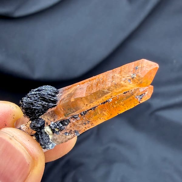 Flame-orange hematoid quartz crystal on black specular hematite from Guangdong, China, close-up of the crystal faces